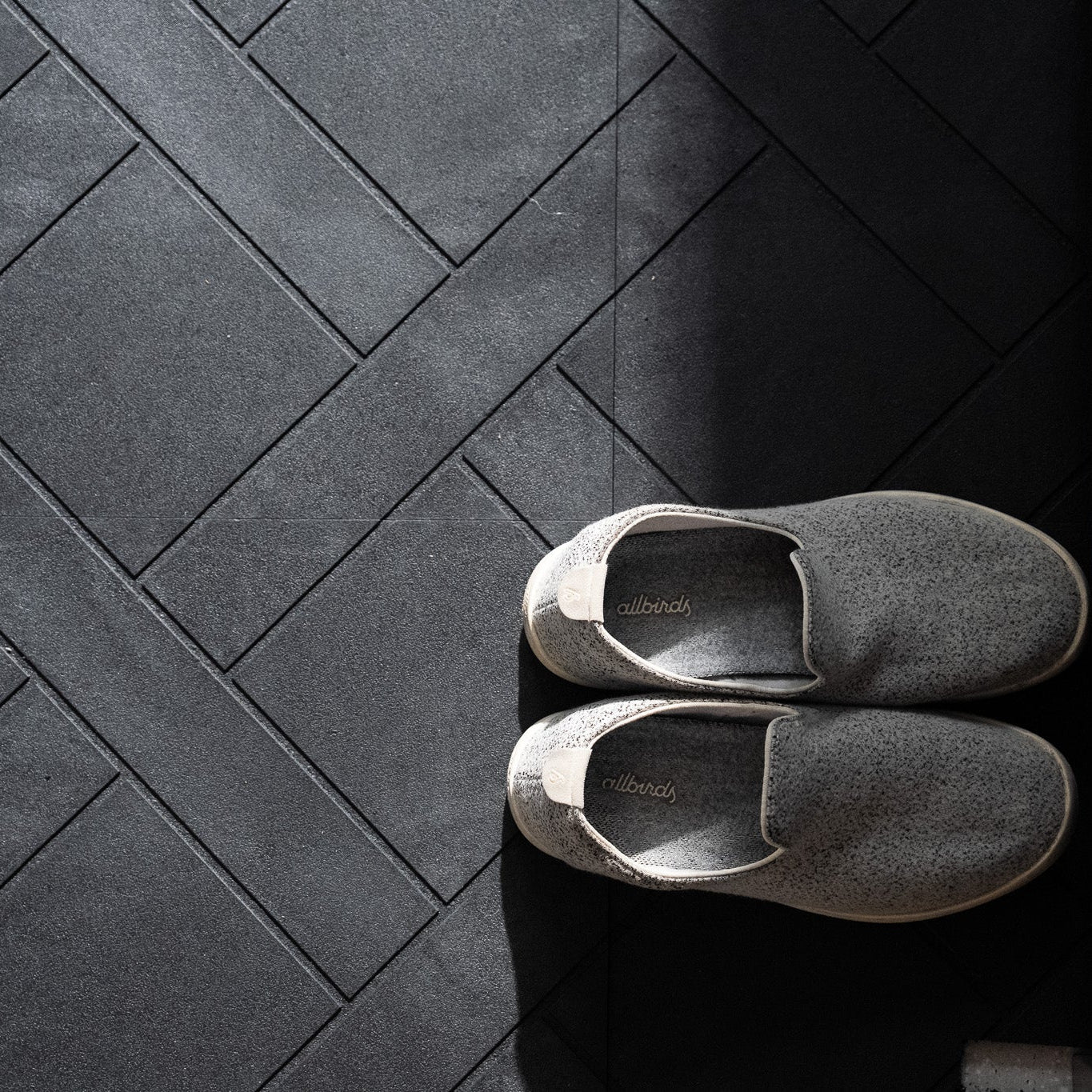 Pair of gray shoes on a dark tiled floor