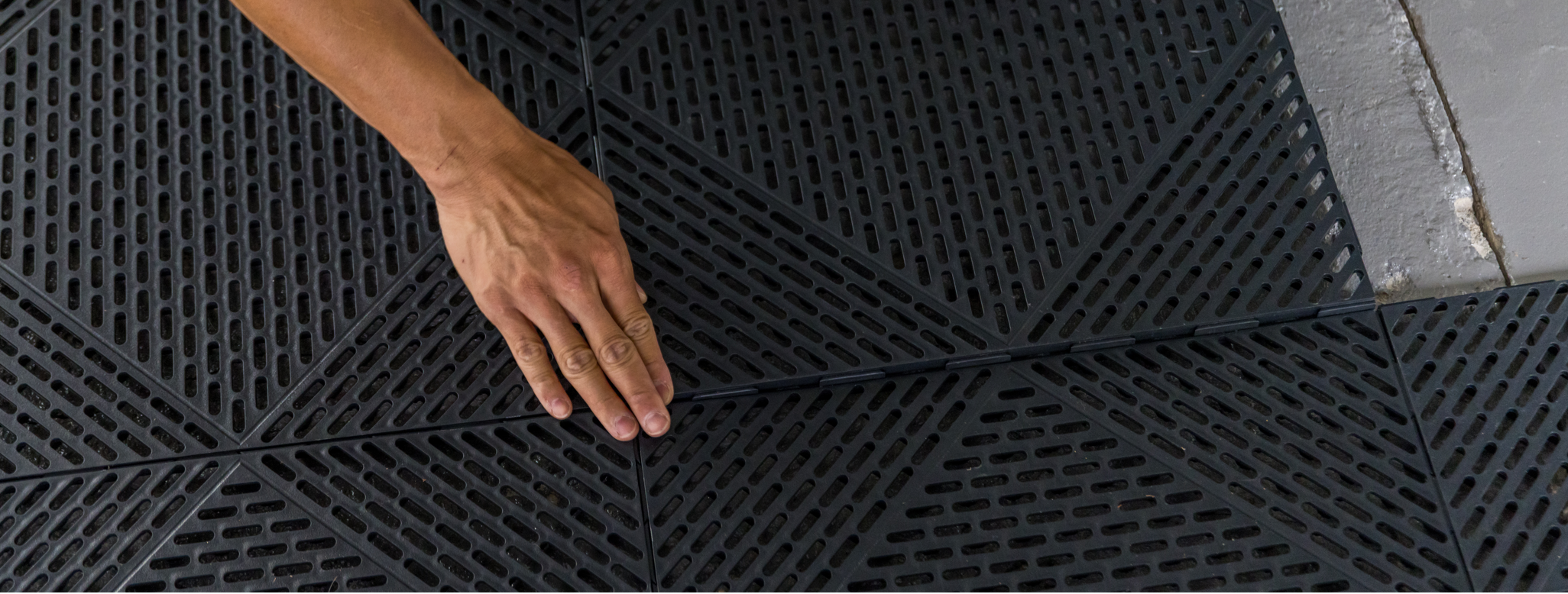 Person doing a tool free assembly of garage tiles 